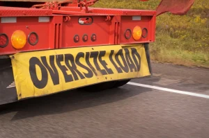 Back of tractor trailer with sign reading Oversize Load