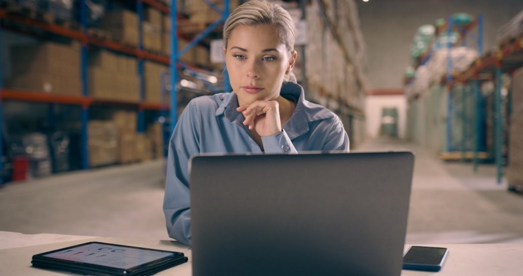 Freight broker in warehouse at computer