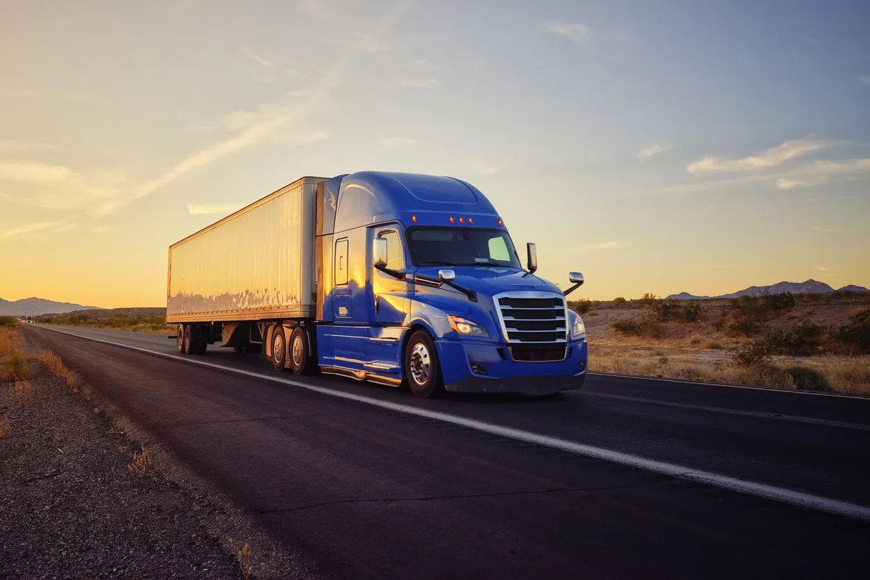 Long semi truck on Midwestern highway at sunset