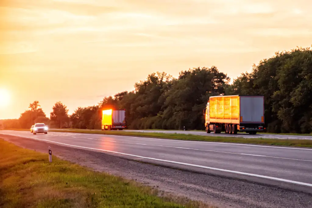 Delivery trucks on the highway at sunset